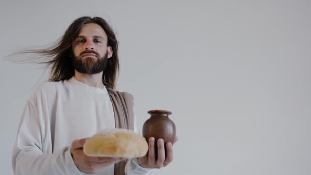 Иисус держит кувшин и хлеб на белом фоне. Студия. Закрыть. - Кадры, видео