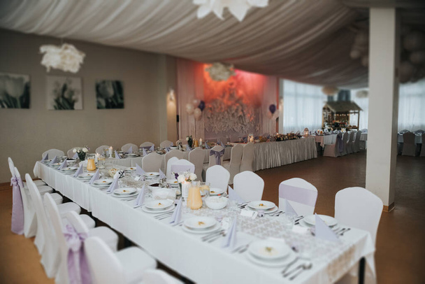 Красиво оформленный свадебный стол и другие детали в свадебном зале. День свадьбы - Фото, изображение