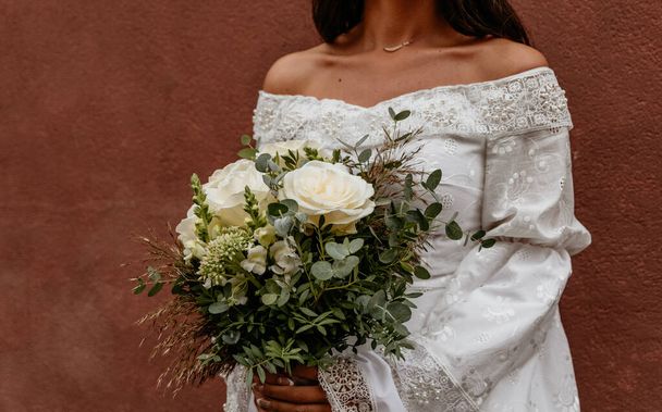Midsection of bride holding white and green boho style wedding flowers bouquet. - Foto, Bild