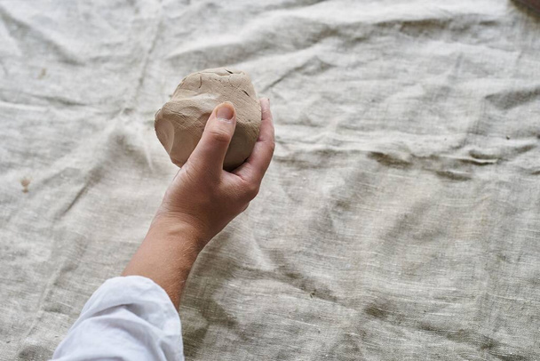 крупним планом жіночі руки замішують шматок глини на столі
 - Фото, зображення