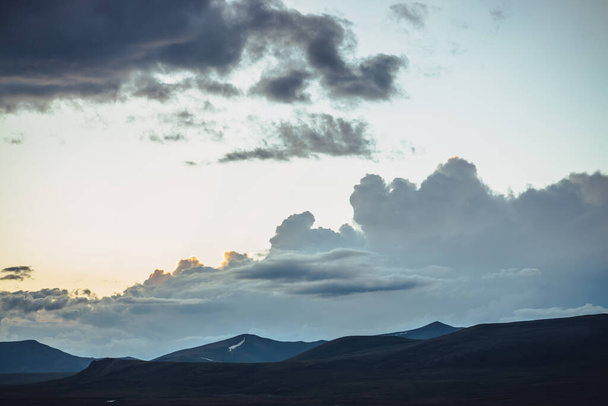 Красиві пейзажі з гірськими силуетами під заходом сонця хмарне небо. Атмосферний гірський пейзаж з силуетом пагорбів на сході сонця. Золоте сонячне світло у вечірньому небі. Жовте світло в хмарному небі
. - Фото, зображення