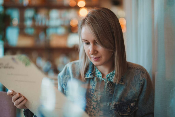 Женщина смотрит меню в ресторане. - Фото, изображение