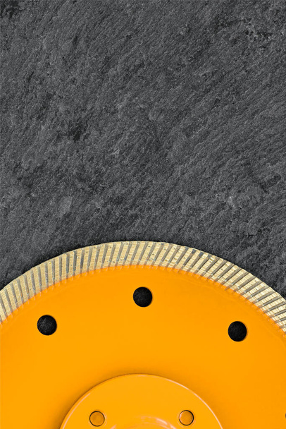 Diamant cut-off wiel met dunne snijsegmenten voor het snijden van steen en graniet, gele cirkel lichaam tegen donker grijs graniet achtergrond, Kopieer ruimte, close-up. Verticaal beeld. - Foto, afbeelding