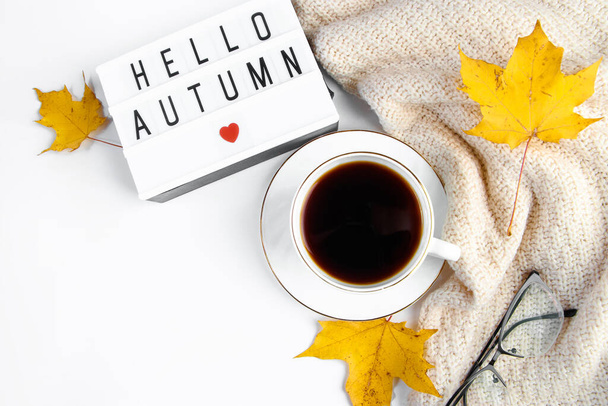 Autumn morning concept. Cup of hot espresso coffee and fallen leaves on a white background. Warm beverage for cold weather and knitted sweater. - Photo, image