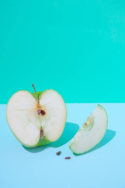 Fruits, diet, eco food and objects concept. Ripe green apple slices on a beautiful pastel blue background with space for product or text advertising, fruit healthy concept. - 写真・画像