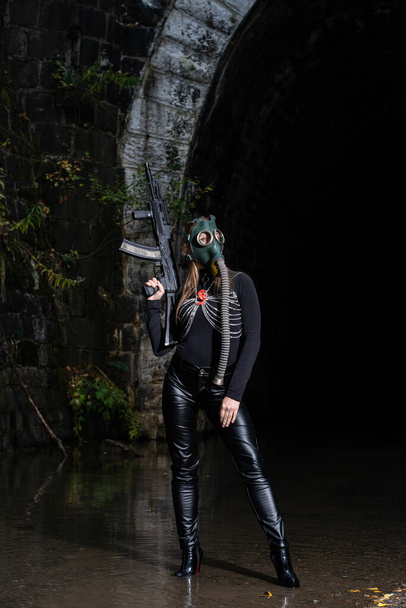 nainen mustassa puvussa ja kaasunaamari käsissään konekivääri - Valokuva, kuva