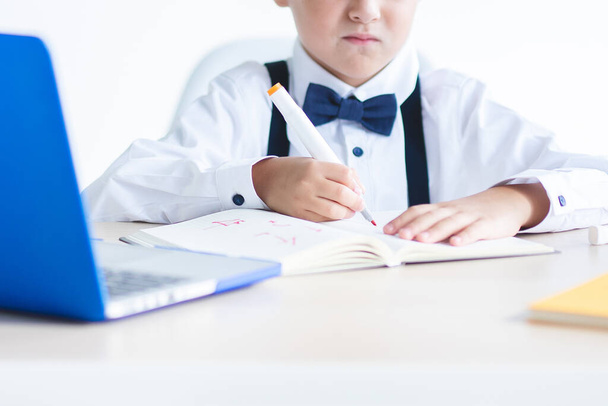 Primary school child writes in notebook. Daylight. Selective focus. Concept for study, education, writing, unhappy student, fine motor skills, back to school, online education. Caucasian child. - Фото, изображение