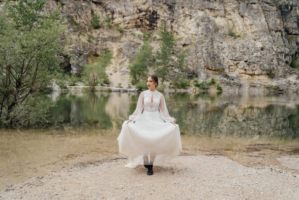 bride in black boots for mountain tourism on the shore of a mountain lake. - Fotoğraf, Görsel