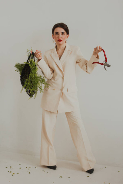Mujer joven en un traje blanco con bolsa de verduras frescas sobre fondo blanco - Foto, imagen