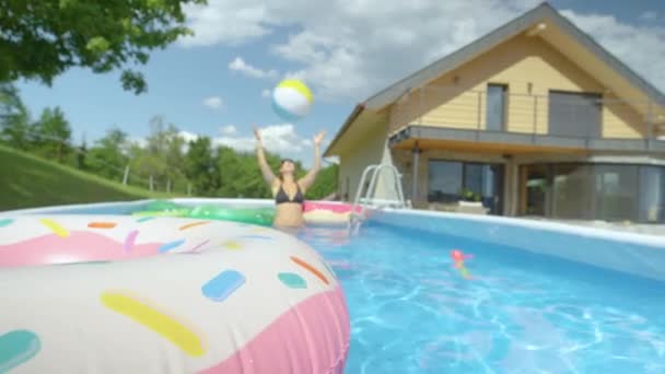 CERRAR: Mujer en bikini negro lanza bola inflable alrededor de su piscina privada. - Imágenes, Vídeo
