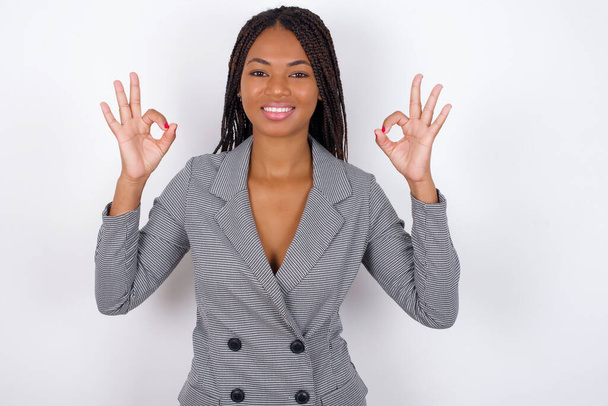 Blij jonge mooie Afrikaanse Amerikaanse zakenvrouw toont ok teken met beide handen als uitdrukt goedkeuring, heeft vrolijke uitdrukking, optimistisch. - Foto, afbeelding