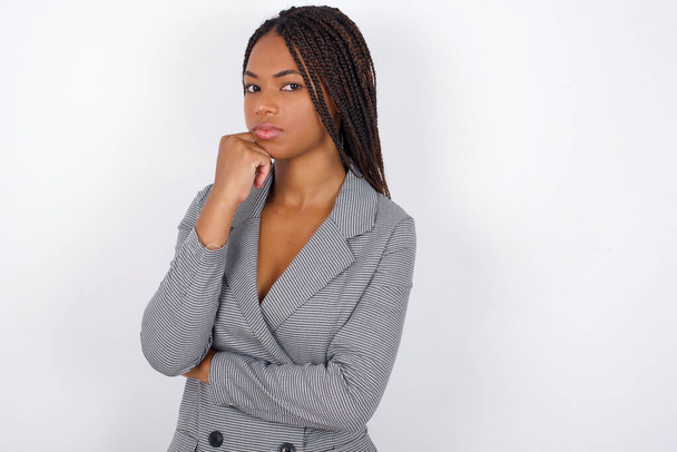 Portrait of thoughtful  young beautiful african american businesswoman  keeps hand under chin, looks away trying to remember something or listens something with interest. Youth concept. - Foto, Imagen