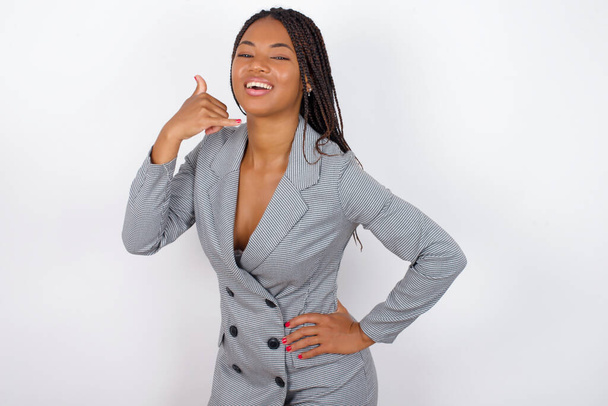  young beautiful african american businesswoman   imitates telephone conversation, makes phone call gesture with hands, has confident expression. Call me! - Photo, Image