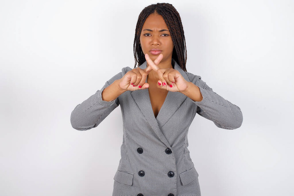 africký americký obchod žena s copánky přes bílou zeď má odmítnutí naštvaný výraz kříž prsty dělá negativní znamení. - Fotografie, Obrázek