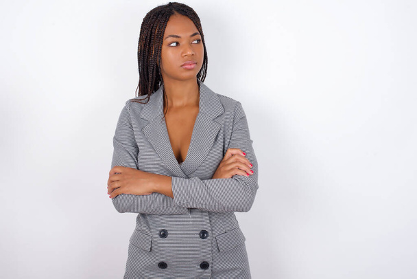 Image of upset Young african american business woman with braids over white wall with arms crossed. Looking with disappointed expression aside after listening to bad news. - Zdjęcie, obraz