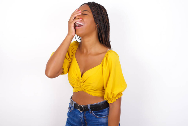 Charismatic carefree joyful  african american woman wearing yelllow top and jeans  likes laugh out loud not hiding emotions giggling hear funny hilarious joke chuckling facepalm. - Foto, Bild