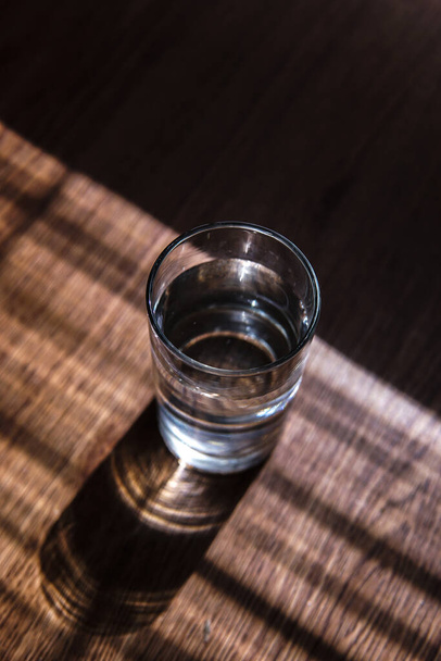 A vertical shot of a glass of water on a sunny table - Fotó, kép