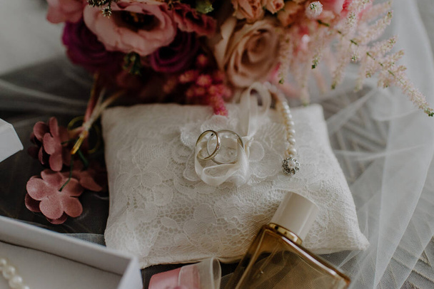A bouquet of fresh flowers, perfume, rings, accessories, and other wedding paraphernalia on the table - Fotó, kép