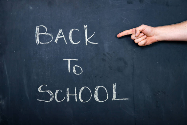 Hand pointing on Back to school text on blackboard. - Foto, Imagen