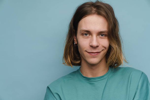 Young white man wearing t-shirt smiling and looking at camera isolated over blue wall - Photo, Image