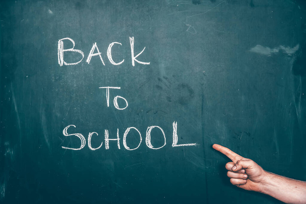 Hand pointing on Back to school text on blackboard. - Zdjęcie, obraz