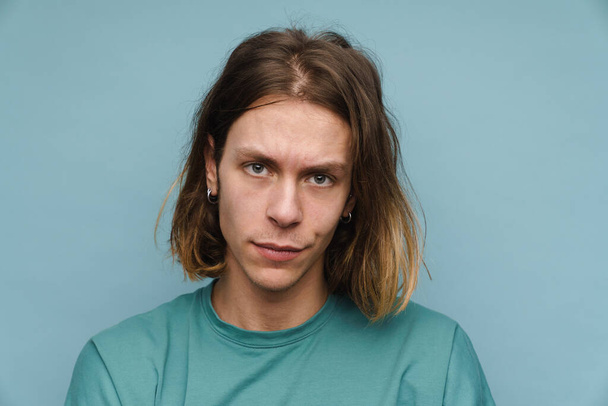 Portrait of a smiling young blonde man in t-shirt standing over blue background looking at camera - Valokuva, kuva