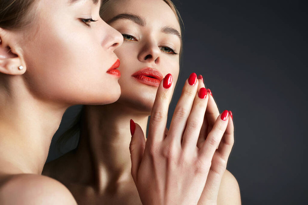 Menina bonita no espelho. Sensual Mulher jovem com lábios vermelhos make-up e manicure vermelho - Foto, Imagem
