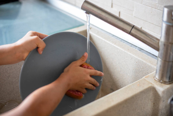 enfant aide à laver la vaisselle dans la cuisine à la maison, confort familial, horizonta - Photo, image