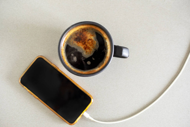 buongiorno telefono tazza di caffè e caricabatterie su sfondo grigio durante l'isolamento Flat Lay - Foto, immagini