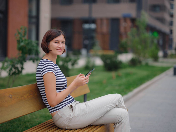 Mujer sonriente usando teléfono móvil en la calle - Foto, Imagen