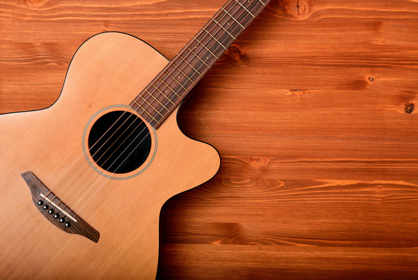 Крупним планом західна гітара на дерев'яному фоні
 - Фото, зображення