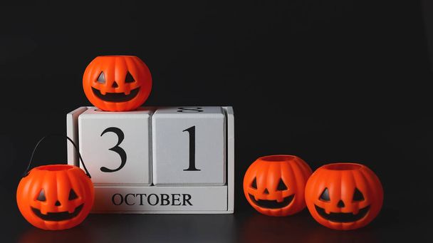Front view of wooden calendar 31 October with plastic Halloween pumpkins  on black background. Halloween holiday or Halloween party concept - Фото, зображення