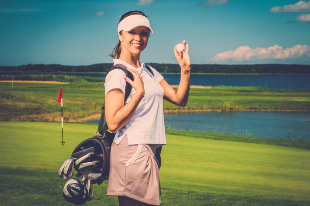 Joven mujer alegre con bolsa y pelota en un campo de golf
 - Foto, imagen
