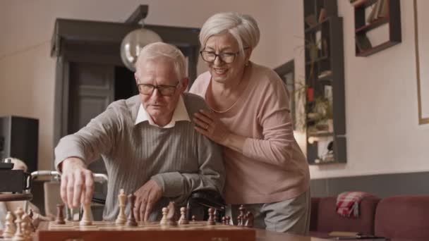 Powolne ujęcie białej pary seniorów spędzającej wolny czas grając w szachy w domu opieki - Materiał filmowy, wideo