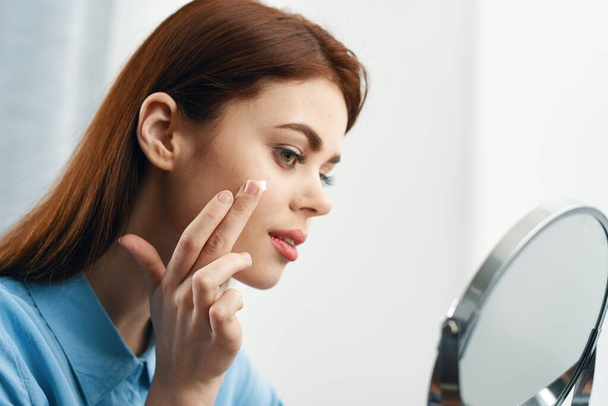 femme regardant dans le miroir cosmétiques soins personnels - Photo, image
