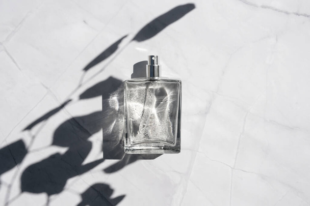 Beyaz mermer yüzeyine sprey sıkılmış saydam bir parfüm şişesi.. - Fotoğraf, Görsel