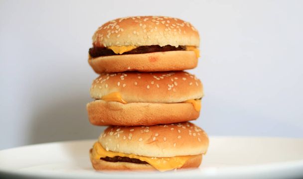 Montón de hamburguesas con queso sobre fondo blanco. - Foto, imagen