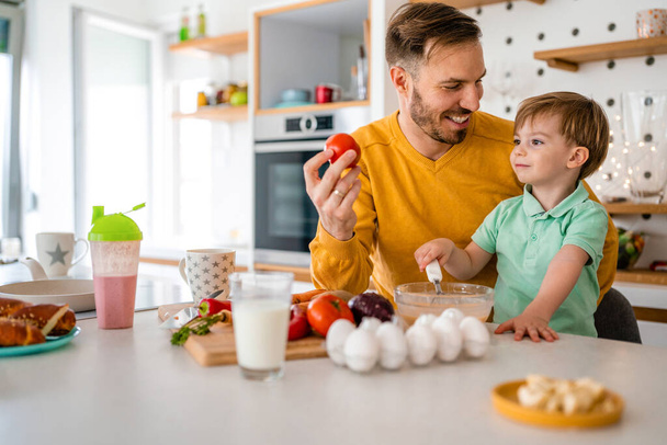 Happy family home fun kitchen concept. Smiling father with children preparing healthy food and spending time together - Фото, зображення
