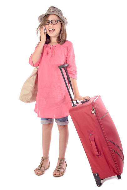 κοριτσάκι με μια κόκκινη βαλίτσα που μιλάει στο τηλέφωνο - Φωτογραφία, εικόνα