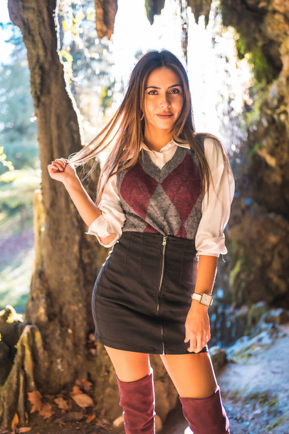 Schoolgirl in a black skirt and maroon boots in a cave one autumn afternoon - Foto, Imagem