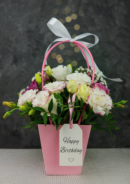 Όμορφο λευκό Eustoma Gypsophila λουλούδια μπουκέτο σε ροζ παστέλ καλάθι σκούρο φόντο. Floral δώρο ανθίζοντας ταπετσαρία, Χρόνια πολλά ευχετήρια κάρτα γιορτή κόμμα πρόσκληση Εορταστική αντίγραφο χώρου. - Φωτογραφία, εικόνα