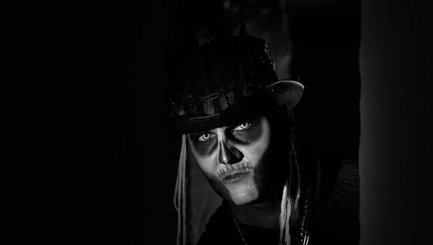 Hombre espeluznante con el esqueleto de Halloween maquillaje aparece de la esquina oscura, tratando de asustar - Foto, imagen