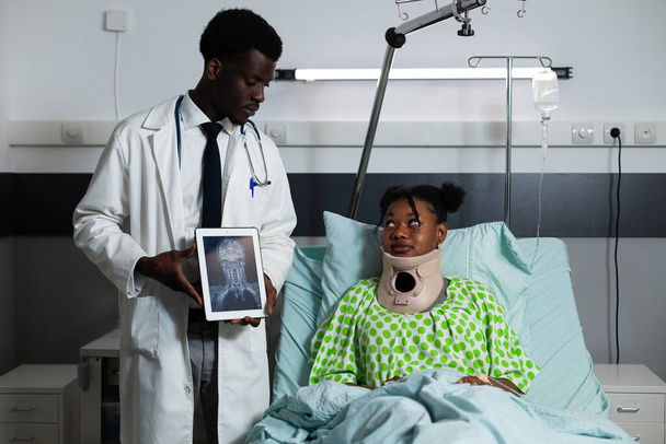 Afrikalı Amerikalı doktor hastaya röntgen tableti gösteriyor. - Fotoğraf, Görsel