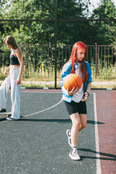Девушка-подросток со скейтбордом на спортивной площадке, размытый передний план - Фото, изображение