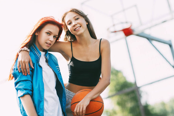 二人の笑顔の女の子がバスケットボールコートに立っている - 写真・画像