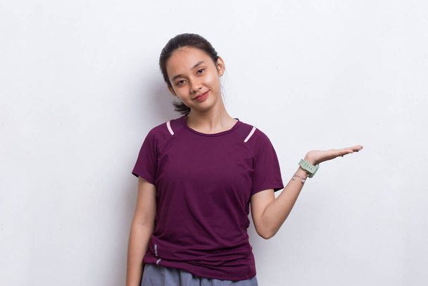 joven asiático deportivo mujer apuntando dedo en vacío espacio en blanco fondo - Foto, Imagen