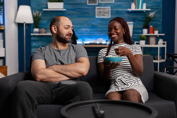 Casal interracial casal rindo e conversando na sala de estar - Foto, Imagem