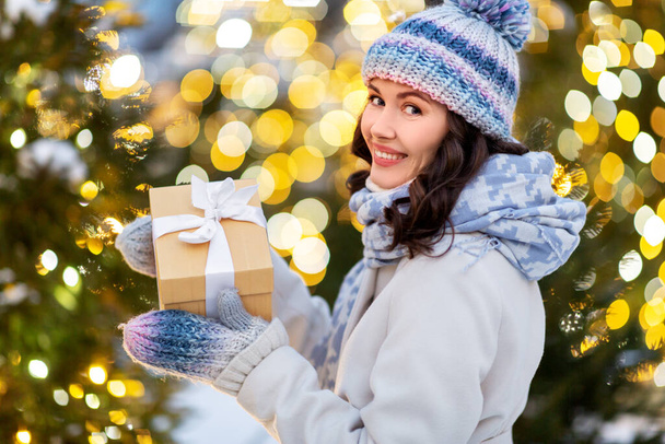 happy woman with christmas gift over lights - Foto, Bild