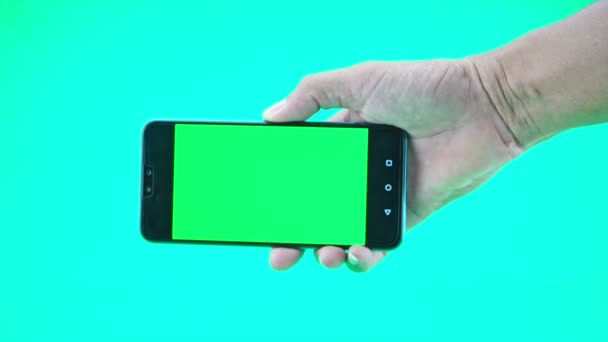 Akıllı telefonu ya da cep telefonunu yeşil ekran arka planında tutan adamın elini kapat - Video, Çekim