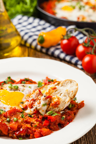 Shakshouka, dish of eggs poached in a sauce of tomatoes, chili peppers, onions. Front view.  - Foto, Imagen